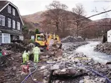  ?? AFP ?? Emergency measure Workers use a machine to excavate the Ulls Water to improve its drainage after it flooded the village following a period of heavy rainfall in Glenriddin­g yesterday.