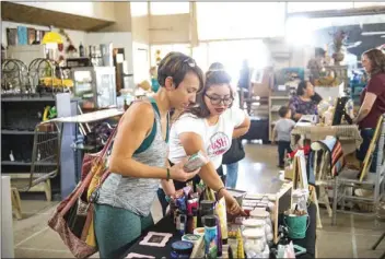  ??  ?? Christina Diaz-Anguiano (right) shows new beauty products from her booth to a customer during the Downtown Dollars event on Saturday afternoon in El Centro. VINCENT OSUNA PHOTO