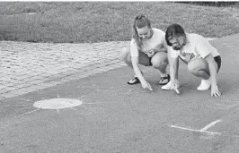  ?? MICHAEL LAUGHLIN/SOUTH FLORIDA SUN SENTINEL ?? Sisters Ellie, left, and Caroline Byrd draw chalk art on Northeast 20th Court, in the Coral Ridge neighborho­od of Fort Lauderdale on Thursday. Across South Florida, especially at Easter and Passover, people are looking for ways to cheer themselves up and for visual reminders of better times ahead.