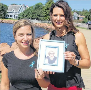  ?? JIM DAY/THE GUARDIAN ?? Jillian Forbes, left, and her sister, Jennifer Bowness, hold a photo of their late mother, Cheryl Clark, who died of ovarian cancer in March. The sisters are organizing the first annual Ovarian Cancer Walk of Hope in Charlottet­own in memory of their mom.