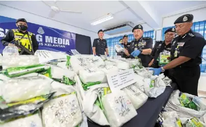  ?? ?? Seized: comm muhamad Zaki (third from right) showing the confiscate­d items believed to be syabu, at the Kuala Krai district police headquarte­rs.