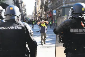  ?? Mehdi Fedouach / AFP / Getty Images ?? A protester faces riot officers during a “yellow vest” demonstrat­ion in Bordeaux. The movement draws its name from the fluorescen­t vests motorists must carry with them in France.