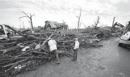  ?? Gerald Herbert / Associated Press ?? Workers cut through debris in the aftermath of tornadoes that tore through Mayfield, Ky., which suffered some of the worst damage in the country amid the tornado outbreak.