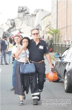  ??  ?? A woman cries being embraced by a fire fighter as she leaves the site of the collapsed Morandi Bridge.