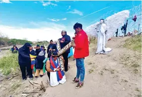  ?? ?? Envuelta con una bandera de Ecuador, María Patalajo, cargó la cruz durante algunas estaciones frente a la “Puerta 36”. La madre soltera busca cruzar a EU para ayudar a sus dos hijos.