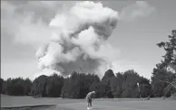  ?? JAE C. HONG / AP ?? Doug Ralston plays golf in Hawaii as a huge ash plume rises from the summit of Kilauea volcano on Monday.