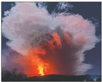  ??  ?? A fiery river of glowing lava flows Wednesday on the north-east side of the Mount Etna volcano engulfed with ashes and smoke.