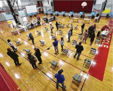  ?? Curtis Compton / Atlanta Journal-Constituti­on via AP ?? Voters socially distance Tuesday while waiting in line to cast their votes in Georgia’s runoff election inside the gymnasium at a middle school in Social Circle, Ga. No major voting problems were reported.