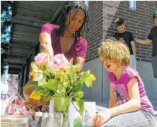  ?? THE ASSOCIATED PRESS ?? Angel Sauls, left, helps her stepdaught­er, Coco Douglas arrange a sign and some painted rocks she made for a memorial in Portland, Ore., for two bystanders who were stabbed to death while trying to stop a man yelling anti-Muslim slurs toward two young...