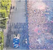  ??  ?? Fan-tastic: The French team are greeted by a huge turn-out of fans on the Champs-Elysee