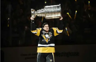  ?? Peter Diana/Post-Gazette ?? Sidney Crosby raises the Stanley Cup during a ceremony before the opening game of the 2016 season at PPG Paints Arena.