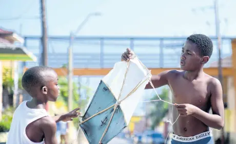  ?? GLADSTONE TAYLOR/ MULTIMEDIA PHOTO EDITOR ?? Nine-year-old Dashawn Brown (left) assists Jahreil Baker, 12, to get a kite airborne on Hanover Street in Kingston on Saturday. Jamaica’s kite season traditiona­lly begins in April, with enthusiast­s taking advantage of favourable winds.