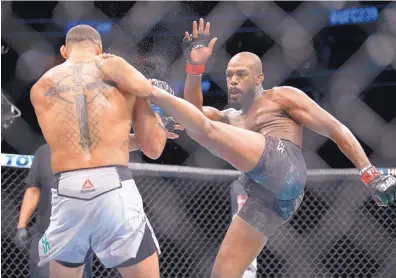  ?? ERIC JAMISON/ASSOCIATED PRESS ?? Jon Jones, right, lands a kick against Brazil’s Thiago Santos during their light heavyweigh­t title bout Saturday night. Jones won the bout by split decision at T-Mobile Arena in Las Vegas, Nev.