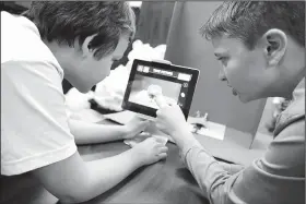  ?? NWA Democrat-Gazette/DAVID GOTTSCHALK ?? Adam Teakell (left) and Brayden Hamilton, both sixth-graders at Sonora Middle School, work Friday on an adventure-themed stop-motion animation video during the lunch hour, at the school. A focus on providing students with a personaliz­ed learning...