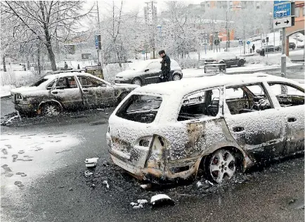  ?? PHOTO: REUTERS ?? A policeman inspects burnt-out cars after the riot in the predominan­tly immigrant suburb of Rinkeby outside Stockholm.