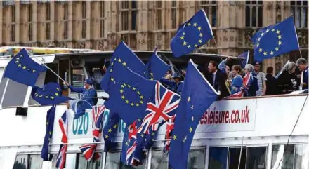  ?? REUTERS PIC ?? Anti-Brexit, pro-European Union Remain supporters wave flags as they travel up and down the River Thames, outside the Houses of Parliament, in London, Britain.