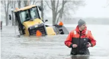  ?? ADRIAN WYLD, CP ?? A member of the Canadian military makes his way past a submerged piece of heavy equipment Monday in Gatineau, Que.