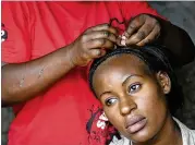  ?? ADELLE KALAKOUTI / ASSOCIATED PRESS ?? Hairdresse­r Mary Wanjiku, 29, weaves the hair of local resident Ruth Njeri, 25, at a makeshift hair salon in the Korogocho slum of Nairobi, Kenya. In one of Africa’s largest dumps, some residents are making a living by collecting and recycling hair...