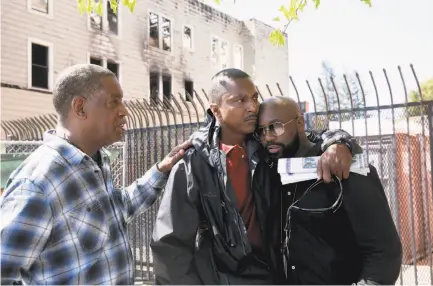  ?? Michael Macor / The Chronicle ?? At the scene of the Oakland fire in which four people died, Leandre Johnson (center), whose wife, Cassandra Robertson, was killed in the blaze, is comforted by Romell Lee (left) and Tywon Lee, Robertson’s brothers.