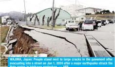  ?? — AFP ?? WAJIMA, Japan: People stand next to large cracks in the pavement after evacuating into a street on Jan 1, 2024 after a major earthquake struck the Noto region in Ishikawa prefecture.