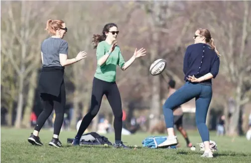  ?? Agence France-presse ?? ↑
Women play with a rugby ball as they enjoy the winter sunshine in Victoria Park in east London on Saturday.