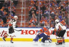  ?? Jeff McIntosh / Associated Press ?? The Ducks’ Jakob Silfverber­g (left) celebrates his goal 45 seconds into overtime as it slams past Oilers goalie Cam Talbot.