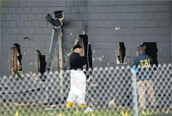  ?? Carolyn Cole Los Angeles Times ?? OFFICIALS EXAMINE the back of the nightclub building. Police punched holes in the cinder-block wall to reach bathrooms where the gunman and club-goers hid.