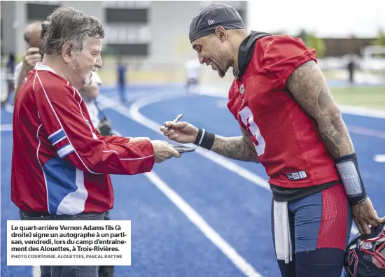  ?? PHOTO COURTOISIE, ALOUETTES, PASCAL RATTHE ?? Le quart-arrière Vernon Adams fils (à droite) signe un autographe à un partisan, vendredi, lors du camp d’entraîneme­nt des Alouettes, à Trois-Rivières.