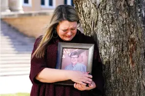  ?? Associated Press ?? ■ Katie Riggs Maxwell begins to cry as she hugs a portrait of her father, Mark Riggs, while standing for a photo Wednesday on the campus of Abilene Christian University in Abilene, Texas. Mark Riggs, who was a professor at the school, died Dec. 14 of COVID-19.