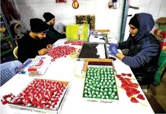  ??  ?? Workers wrap and pack chocolates at al-Arees factory in Gaza City.