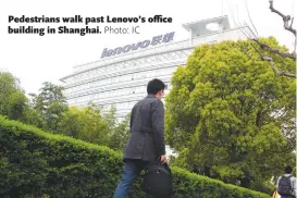  ??  ?? Pedestrian­s walk past Lenovo’s office building in Shanghai.