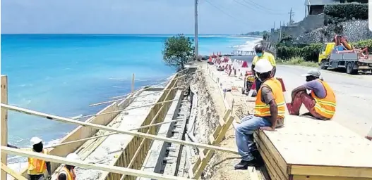  ??  ?? Members of the NWA work to reconstruc­t a sea wall on Wharf Road in Morant Bay, St Thomas, that was destroyed by heavy rains years ago.