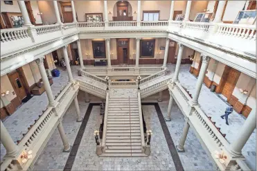  ?? Alyssa Pointer/Atlanta Journal-Constituti­on via AP ?? A Georgia State Trooper (right) walks the empty hallways of the Georgia State Capitol building during the 29th day of the Georgia Legislativ­e session, Friday in Atlanta. Out of caution and in relation to the coronaviru­s, the Georgia General Assembly suspended the legislativ­e session until further notice.