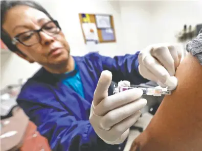  ?? ASSOCIATED PRESS FILE PHOTO ?? Ana Martinez, a medical assistant at the Sea Mar Community Health Center in Seattle, gives a patient a flu shot earlier this month. Despite earlier estimates, the Centers for Disease Control and Prevention said Friday this flu season still hasn’t hit...