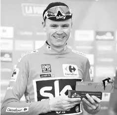  ??  ?? Sky’s British cyclist Christophe­r Froome smiles as he sports the overall leader’s red jersey on the podium of the 20th stage of the 72nd edition of “La Vuelta”Tour of Spain cycling race, a 117.5 km route from Corvera de Asturias to Alto de L’Angliru close to Grandiella, on September 9, 2017. Chris Froome virtually secured overall victory in the Vuelta a Espana yesterday by extending his lead over Vincenzo Nibali as Alberto Contador won the 20th queen stage in his final race before retirement. - AFP photo