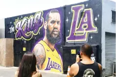  ?? — AFP photo ?? People photograph a mural of LeBron James in a Los Angeles Lakers jersey painted by Jonas Never and Menso One in Venice, California to welcome James to his new team.