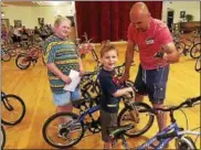  ?? PHOTO COURTESY COMMUNITY BIKES ?? Volunteer Scott Truett helps fit a family with just the right bike at Community Bikes Day on June 11.