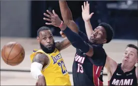  ?? AP photo ?? The Lakers’ LeBron James passes the ball while pressured by the Heat’s Bam Adebayo during the second half of Game 1 of the NBA Finals Wednesday, in Lake Buena Vista, Fla.