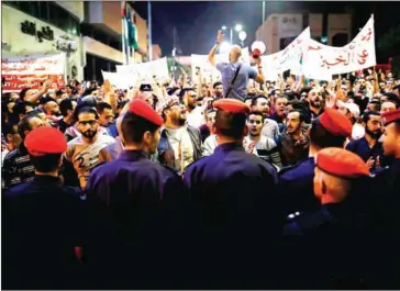  ?? AHMAD GHARABLI/AFP ?? Police stand in front of demonstrat­ors shouting and gesturing during a protest near the prime minister’s office in Amman, Jordan, on Tuesday.