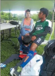  ??  ?? Khin Maung Tint sits with his wife and son during the Redeemer Cup in Proctor Park, a soccer tournament meant to foster ties among different communitie­s in Utica.