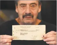  ?? Tyler Sizemore / Hearst Connecticu­t Media ?? Vietnam veteran Ralph Del Vecchio holds an uncashed $82 check for his wartime grave registrati­on duty inside his home in Stamford.