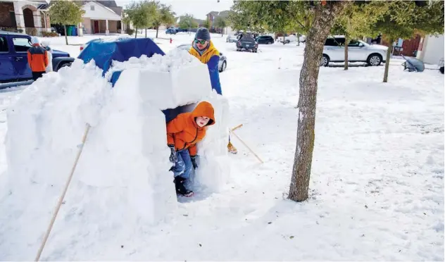  ?? Reuters ?? ↑ Brett Archibad helps his son build an Igloo in front of their home in Pflugervil­le, Texas, on Tuesday.