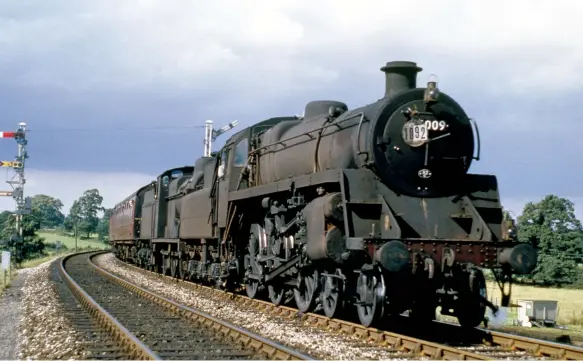  ?? John Dewing/Colour-Rail.com/SD203 ?? Later the same day, BR Standard ‘4MT’ 4-6-0 No 75009 and S&D Fowler ‘4F’ 0-6-0 No 44559 near Templecomb­e under a stormy sky with 1O92, the 7am from Cleethorpe­s to Exmouth on 25 August 1962. Maunsell ‘U’ class 2-6-0 No 31836 will relieve the pair in the station stop (between 3.32-3.37pm) and work the train to Sidmouth Junction, before running light back home to Exmouth Junction shed. As with many summer-dated trains, there were two sets of carriages which would spend the week between trains festering in sidings – for this train there was an SR green set and the Eastern Region set seen here. Exmouth was a lucrative destinatio­n for British Railways and with the S&D erased from routing options the following summer, 1963 saw a new overnight service from Manchester introduced via former GWR lines at Taunton on Friday, and returning via the same route on Saturday morning.