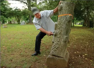  ?? NWA Democrat-Gazette/ANDY SHUPE ?? Bob Young, administra­tor of the Fayettevil­le Evergreen Cemetery Associatio­n, demonstrat­es how easy it is to topple an unsecured Woodmen of the World tombstone Thursday in the cemetery in Fayettevil­le. Young works to clean, secure and repair gravestone­s...