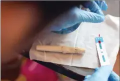  ?? TANG CHHIN SOTHY/AFP ?? A health official checks a blood sample from a villager during a screening for HIV in Kandal province in February last year.