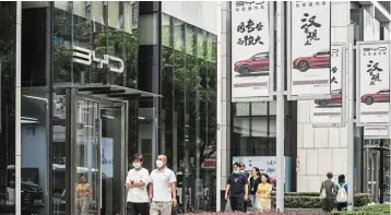  ?? — Bloomberg ?? On the rise: People walk past a BYD showroom in Shanghai. The company took the second spot in the global EV battery rankings in July, overtaking LG Energy, as Chinese firms led overall growth in the industry.