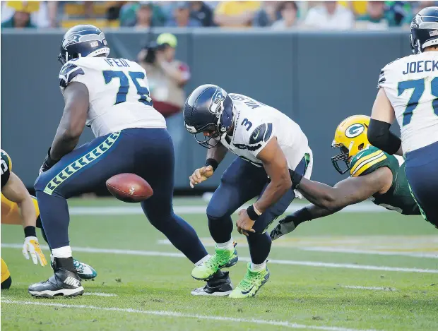  ?? JOE ROBBINS/ GETTY IMAGES ?? Seattle Seahawks quarterbac­k Russell Wilson fumbles the football as he is hit by Green Bay Packers defensive lineman Mike Daniels in the third quarter on Sunday in Green Bay, Wis. Wilson’s offence couldn’t manage a touchdown as the Packers won 17-9.