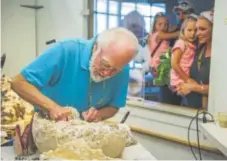  ?? Daniel Brenner, Special to The Denver Post ?? Volunteer Don Brandborg on Saturday begins to prepare the triceratop­s fossils under the watchful gaze of Justin and Tamra Beard and their 5-year-old daughters, Ashlynn, left, and Braelynn, at the Denver Museum of Nature & Science.