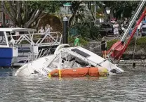  ?? Tanya White / Associated Press ?? People look at a damaged boat in Tutukaka, New Zealand, after tsunami waves from an undersea volcanic eruption swept in.