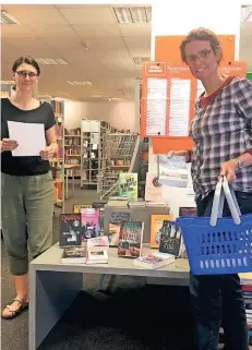  ??  ?? Ab ins Körbchen: Uta Krüger (l.) und Annette Kremer von der Niederkrüc­htener Bibliothek stellen Lesepakete zum Abholen zusammen.